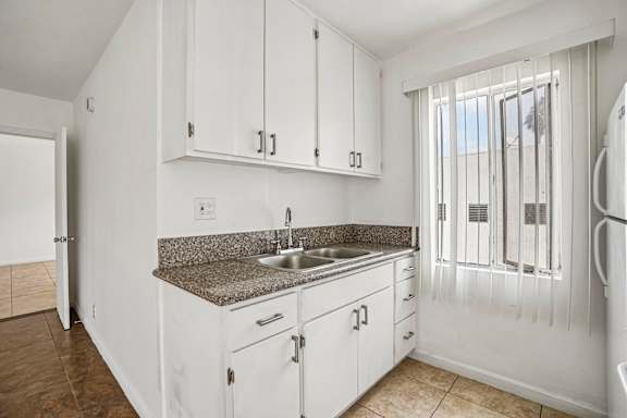 A kitchen with white cabinets and a granite countertop.