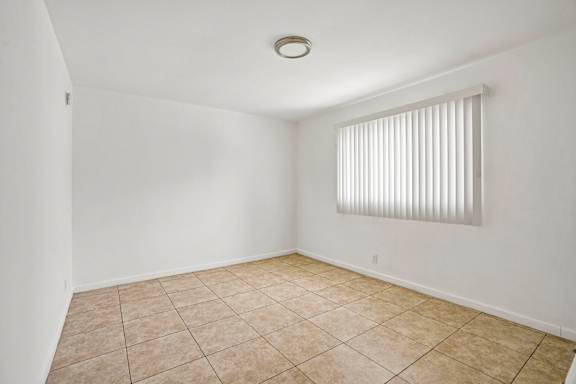 A room with a tiled floor and a window with blinds.