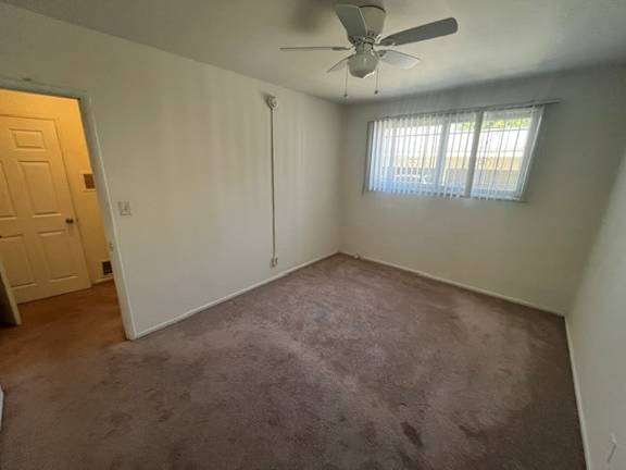 A room with a ceiling fan and a window with blinds.