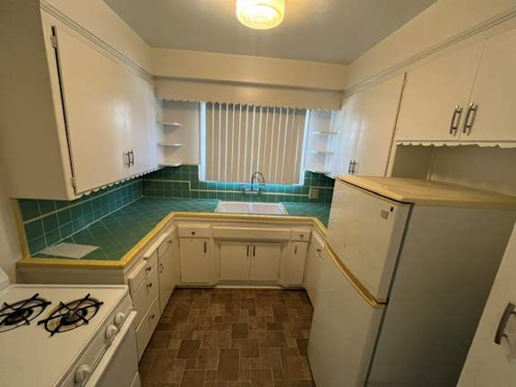 A kitchen with white cabinets and a tiled backsplash.