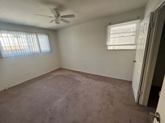 A room with a ceiling fan and carpeted floor.