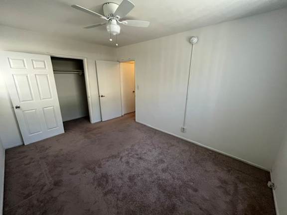A room with a ceiling fan and carpeted floor.