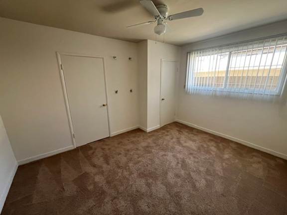 A room with a ceiling fan and carpeted floor.