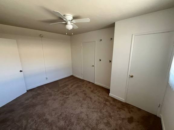 A room with a ceiling fan and carpeted floor.