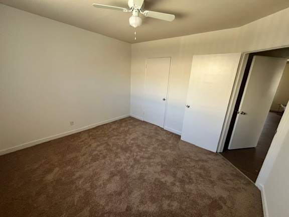A room with a ceiling fan and carpeted floor.