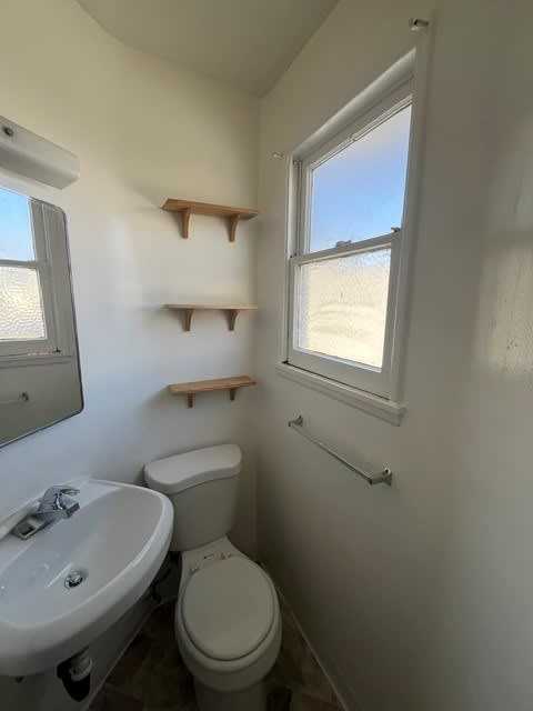 A white bathroom with a toilet, sink, and window.