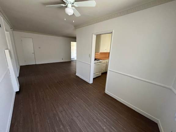 A room with a ceiling fan and wooden flooring.