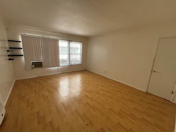 A room with wooden flooring and a window with blinds.