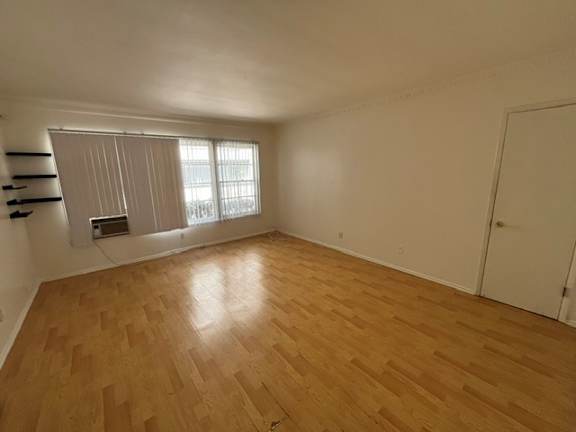 Empty room with wooden flooring and white walls.
