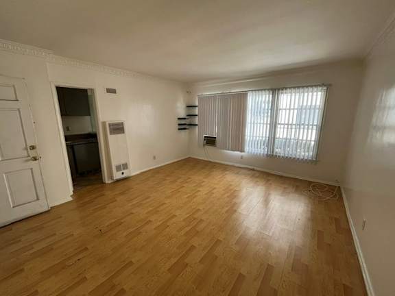 A room with wooden flooring and a window with blinds.