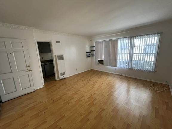 A room with wooden flooring and a window with blinds.