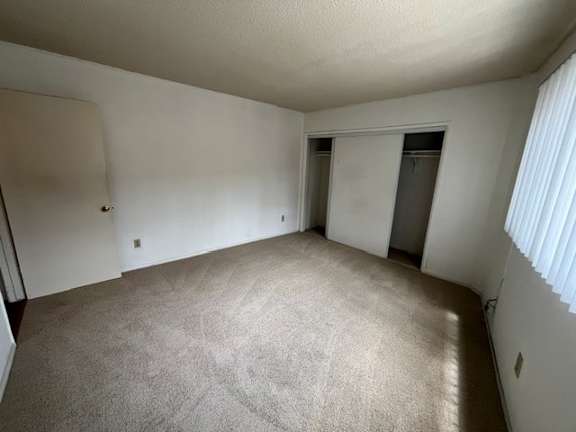 A room with a carpeted floor and a doorway leading to another room.