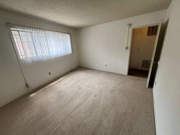 A room with a carpeted floor and a window with blinds.