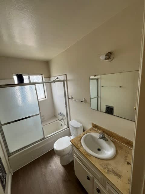 A bathroom with a sink, toilet, and a window.