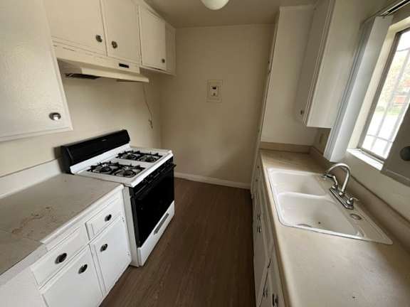 A small kitchen with a stove, sink, and cabinets.