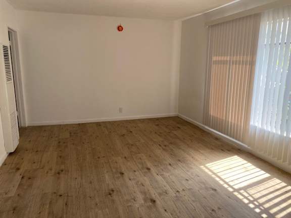 A room with wooden flooring and a window with blinds.