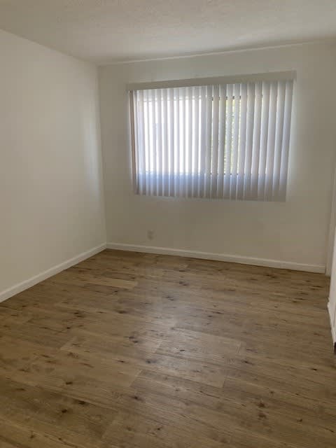 A room with wooden flooring and a window with blinds.