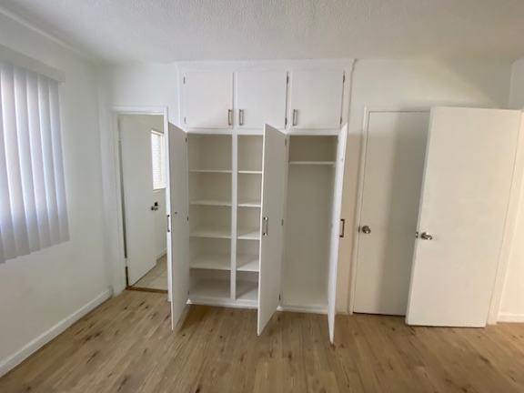 A room with white cupboards and wooden floors.