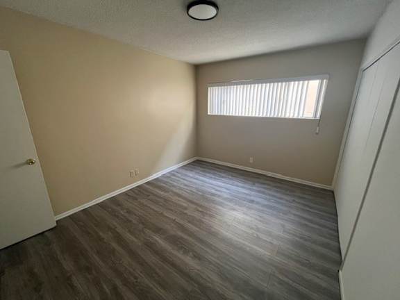 A room with a wooden floor and a window with blinds.