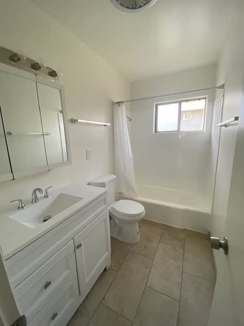 A white bathroom with a toilet, sink, and shower.