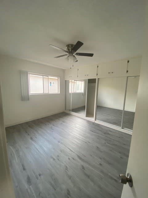 A room with a ceiling fan and wooden flooring.