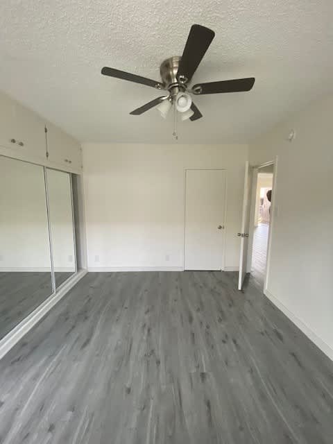 A room with a ceiling fan and wood flooring.