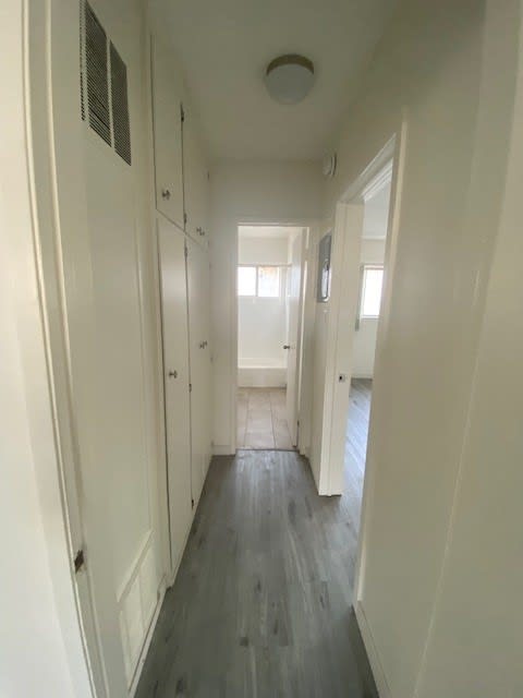 A long hallway with white walls and wood floors.