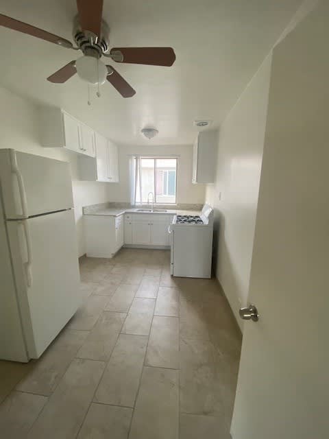A kitchen with a white refrigerator and a ceiling fan.