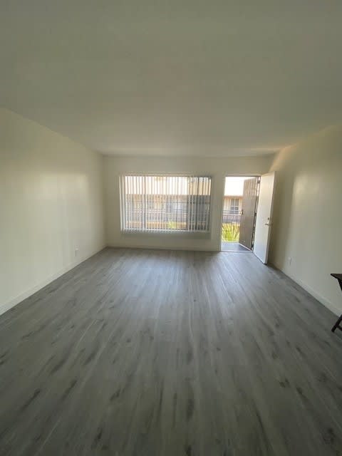 A room with wooden flooring and a window with blinds.