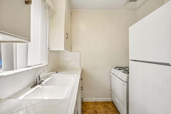 A white kitchen with a sink and a stove.