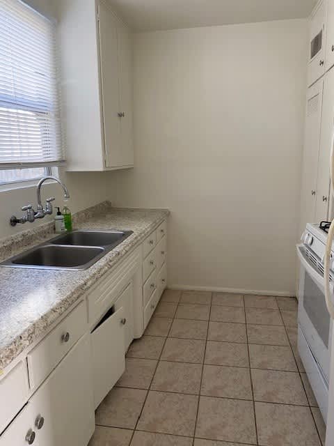 A kitchen with white cabinets and a tiled floor.