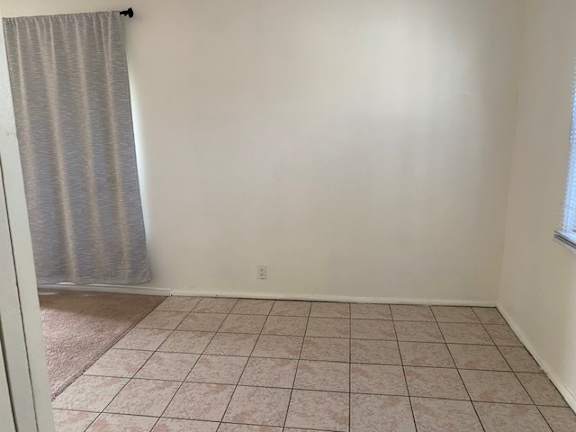 A room with a tiled floor and a window with a curtain.