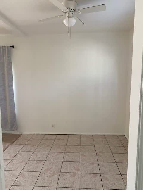 A room with a ceiling fan and tiled floor.