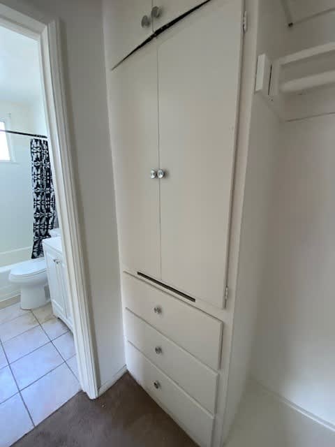 A white bathroom with a toilet and a cabinet.