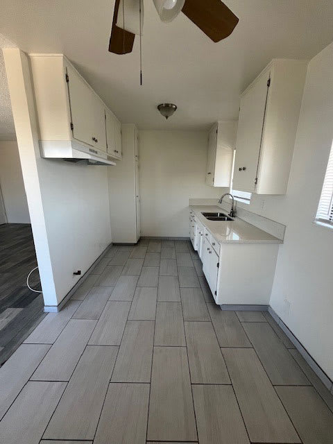A kitchen with white cabinets and a fan.