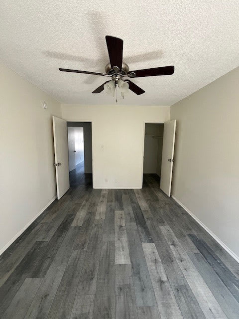 A room with a ceiling fan and wood flooring.