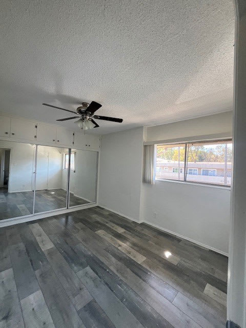 A room with a ceiling fan and a large window.