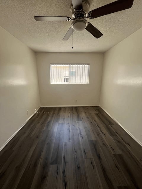 A room with a ceiling fan and wooden flooring.