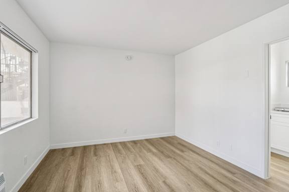 Empty room with wooden flooring and white walls.