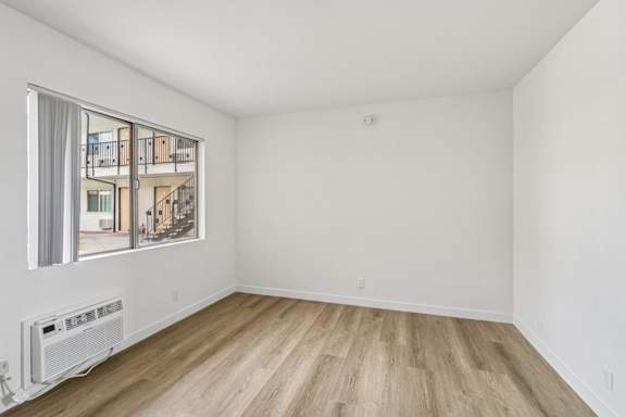 A room with a window showing a balcony outside.