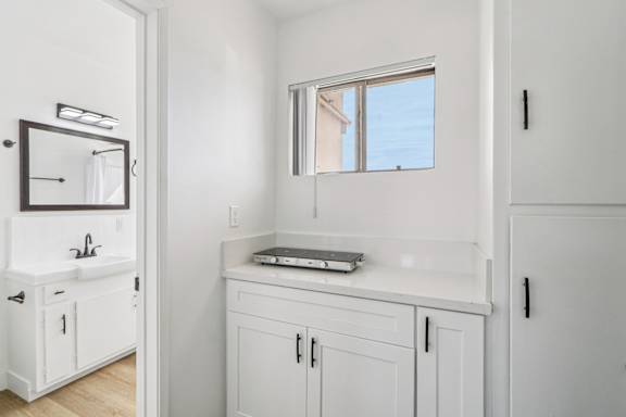 A bathroom with a white vanity and a mirror above it.