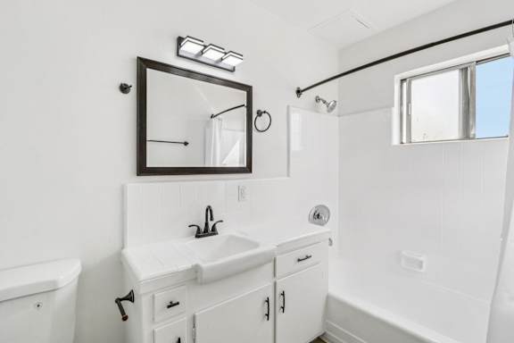 A white bathroom with a sink, mirror, and bathtub.