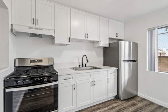 A kitchen with white cabinets and a black stove top oven.