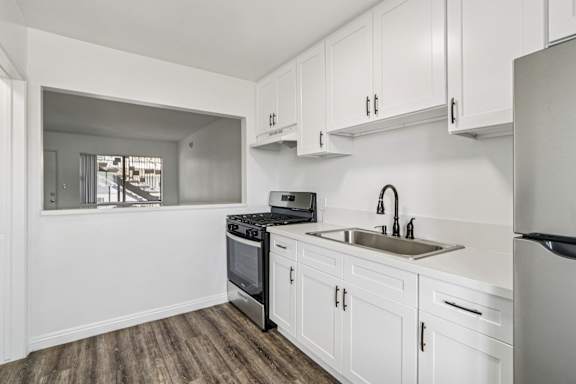 A kitchen with white cabinets and a stainless steel sink.
