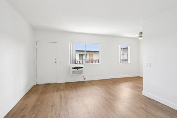 A room with a white door and a window with a view of a building.