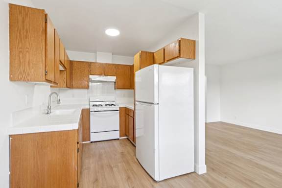 A kitchen with wooden cabinets and white appliances.