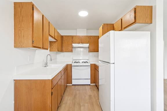 A kitchen with wooden cabinets and white appliances.