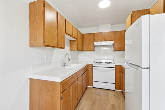 A kitchen with wooden cabinets and white appliances.