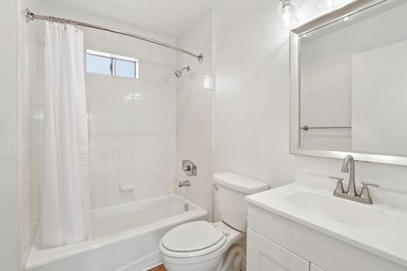 A white bathroom with a toilet, sink, and bathtub.