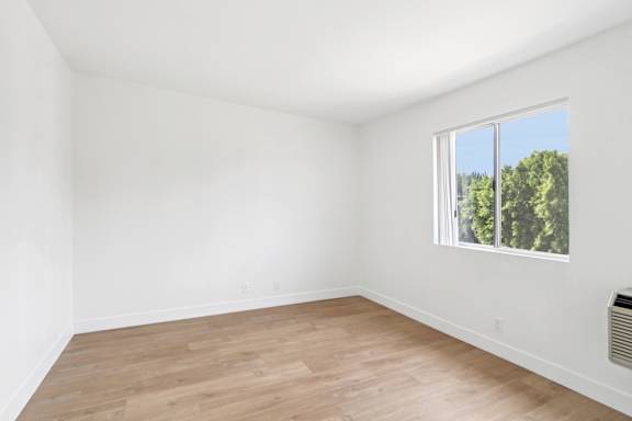 Empty room with a window showing trees outside.